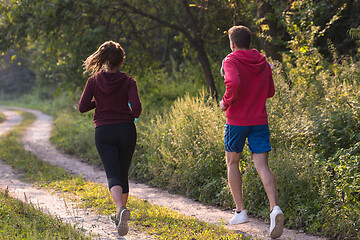 Image showing young couple jogging along a country road