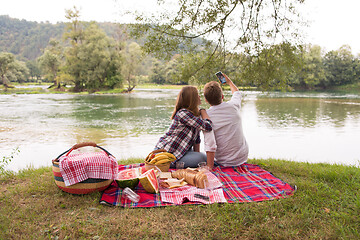 Image showing Couple taking a selfie by mobile phone while enjoying picnic tim