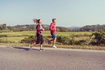 Image showing young couple jogging along a country road