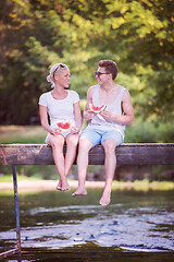 Image showing couple enjoying watermelon while sitting on the wooden bridge