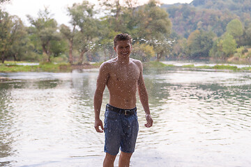 Image showing man with a bare torso splashing water