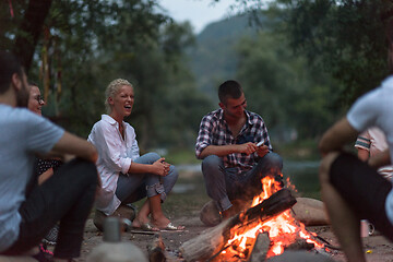 Image showing young friends relaxing around campfire