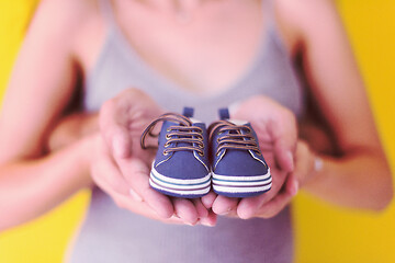 Image showing couple holding newborn baby shoes