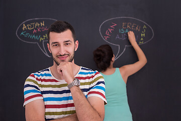 Image showing pregnant couple writing on a black chalkboard