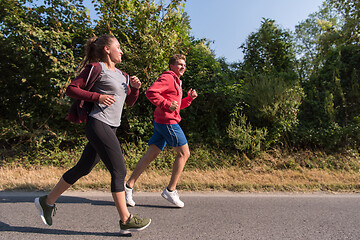 Image showing young couple jogging along a country road