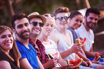 Image showing friends enjoying watermelon while sitting on the wooden bridge