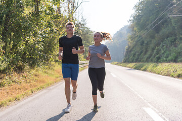 Image showing young couple jogging along a country road