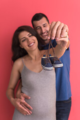 Image showing young pregnant couple holding newborn baby shoes