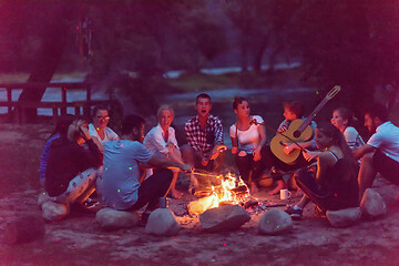 Image showing young friends relaxing around campfire