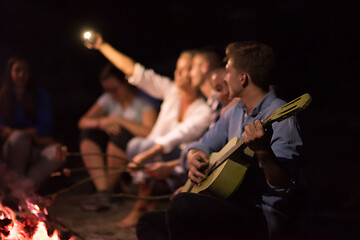 Image showing young friends relaxing around campfire