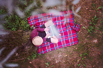 Image showing top view of man using a laptop computer under the tree