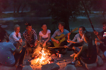 Image showing young friends relaxing around campfire