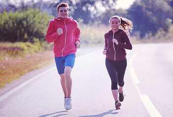 Image showing young couple jogging along a country road