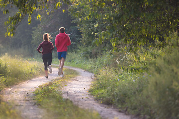 Image showing young couple jogging along a country road