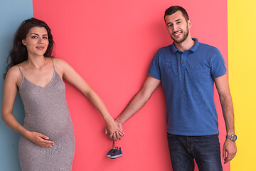 Image showing young happy couple holding newborn baby shoes