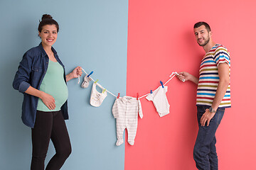 Image showing young couple holding baby bodysuits