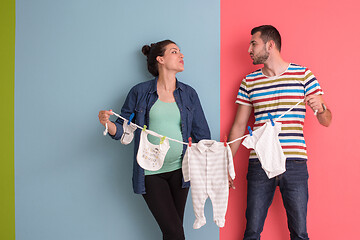 Image showing young couple holding baby bodysuits