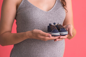 Image showing pregnant woman holding a tiny baby shoes