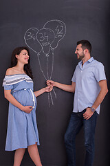 Image showing pregnant couple drawing their imaginations on chalk board