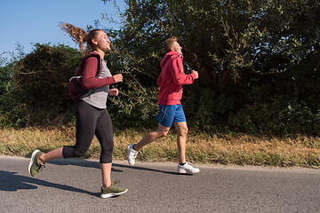 Image showing young couple jogging along a country road