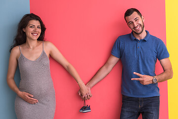 Image showing young happy couple holding newborn baby shoes