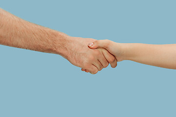 Image showing Closeup shot of human holding hands isolated on blue studio background.