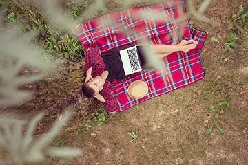 Image showing top view of man using a laptop computer under the tree