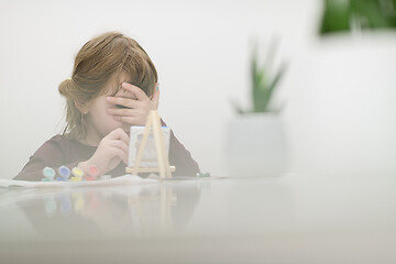 Image showing little girl painting on canvas and hiding face