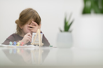 Image showing little girl painting on canvas and hiding face