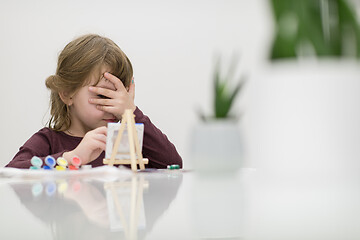 Image showing little girl painting on canvas and hiding face