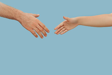 Image showing Closeup shot of human holding hands isolated on blue studio background.