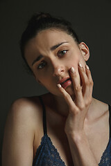 Image showing Half-length portrait of young sad woman on dark studio background