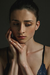 Image showing Half-length portrait of young sad woman on dark studio background