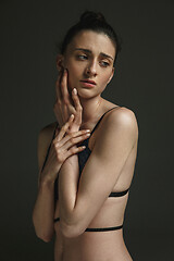 Image showing Half-length portrait of young sad woman on dark studio background