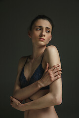 Image showing Half-length portrait of young sad woman on dark studio background