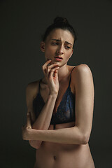 Image showing Half-length portrait of young sad woman on dark studio background