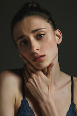 Image showing Half-length portrait of young sad woman on dark studio background