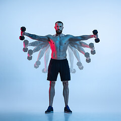 Image showing Young caucasian bodybuilder training over blue background