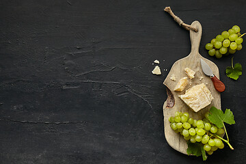Image showing Top view of tasty cheese plate with the fruit on the black stone
