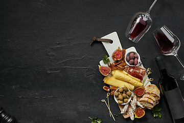 Image showing Two glasses of red wine and cheese plate with fruit on the black stone