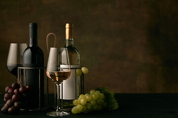 Image showing Front view of tasty fruit plate with the wine bottle on dark studio background