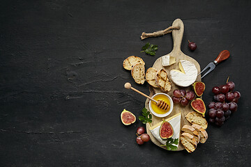 Image showing Two glasses of red wine and cheese plate with fruit on the black stone