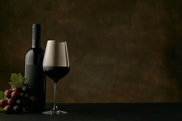 Image showing Front view of tasty fruit plate with the wine bottle on dark studio background