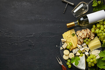 Image showing Top view of tasty cheese plate with fruit on the black stone