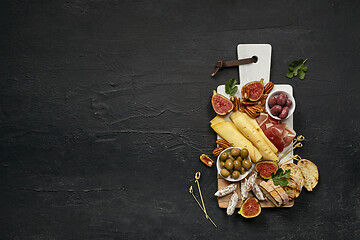 Image showing Top view of tasty cheese plate with the fruit on the black stone