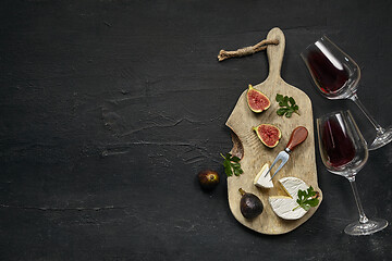 Image showing Two glasses of red wine and a tasty cheese plate on a wooden kitchen plate.