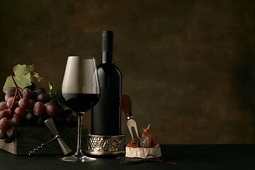 Image showing Front view of tasty fruit plate with the wine bottle on dark studio background