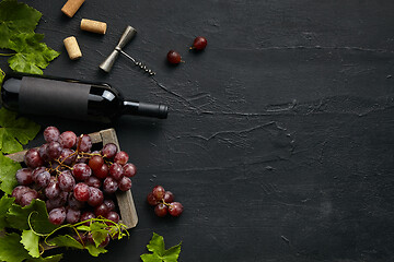 Image showing Top view of tasty fruit plate with the wine bottle on the black stone