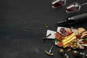 Image showing Two glasses of red wine and cheese plate with fruit on the black stone