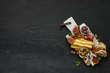 Image showing Top view of tasty cheese plate with the fruit on the black stone